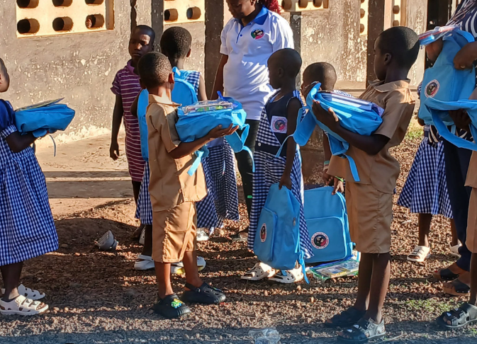 Enfants ivoiriens en uniforme bleu recevant des kits scolaires à Mahapleu, Côte d'Ivoire